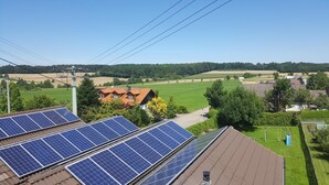 Solar panels on a building roof, surrounded by green fields and trees. - Landgasthof Metzgerei Traube (Heidenheim an der Brenz)