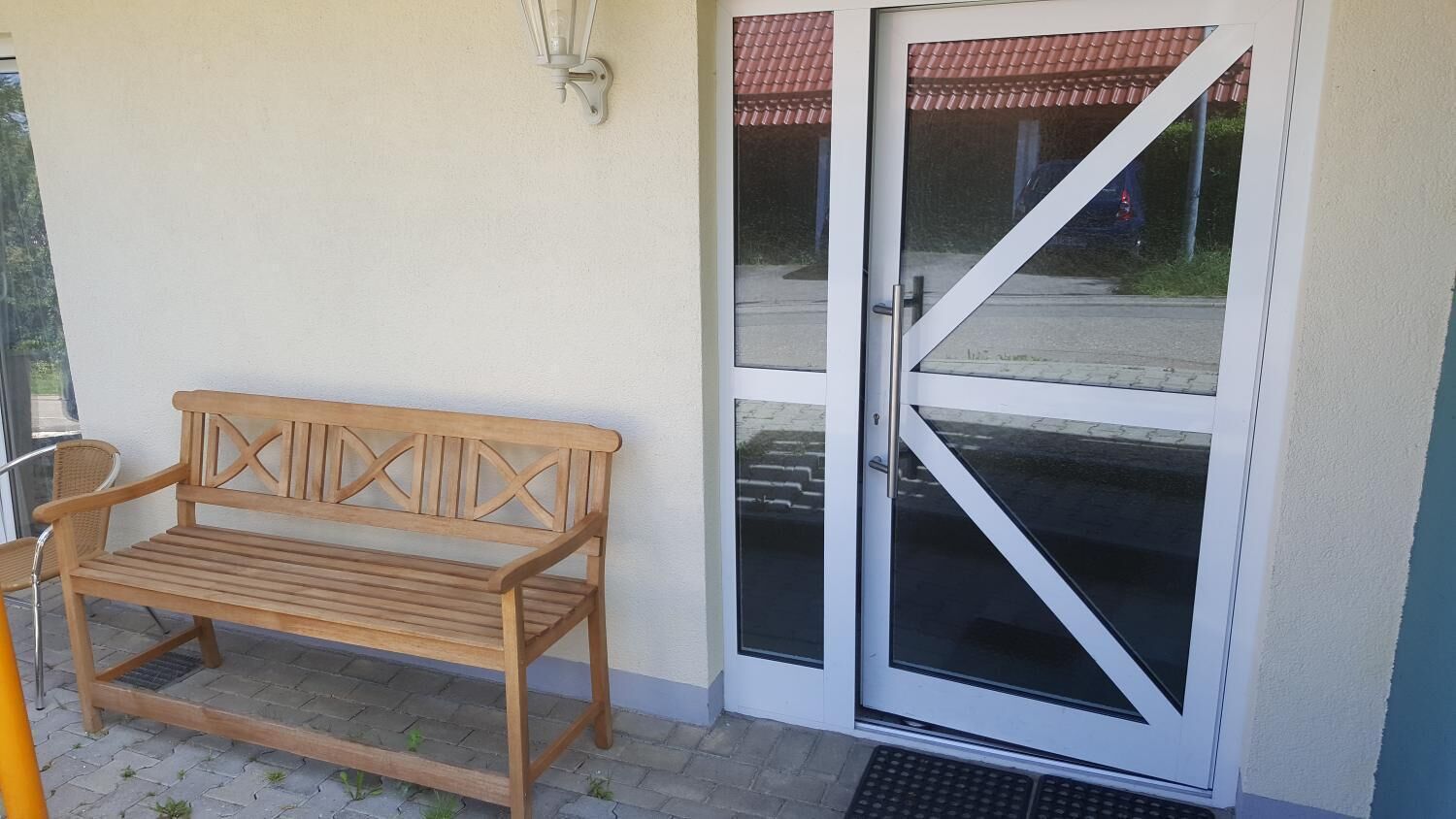 A wooden bench outside a building with a glass door.