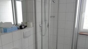 A modern bathroom with a glass-enclosed shower, a white sink, and a toilet.