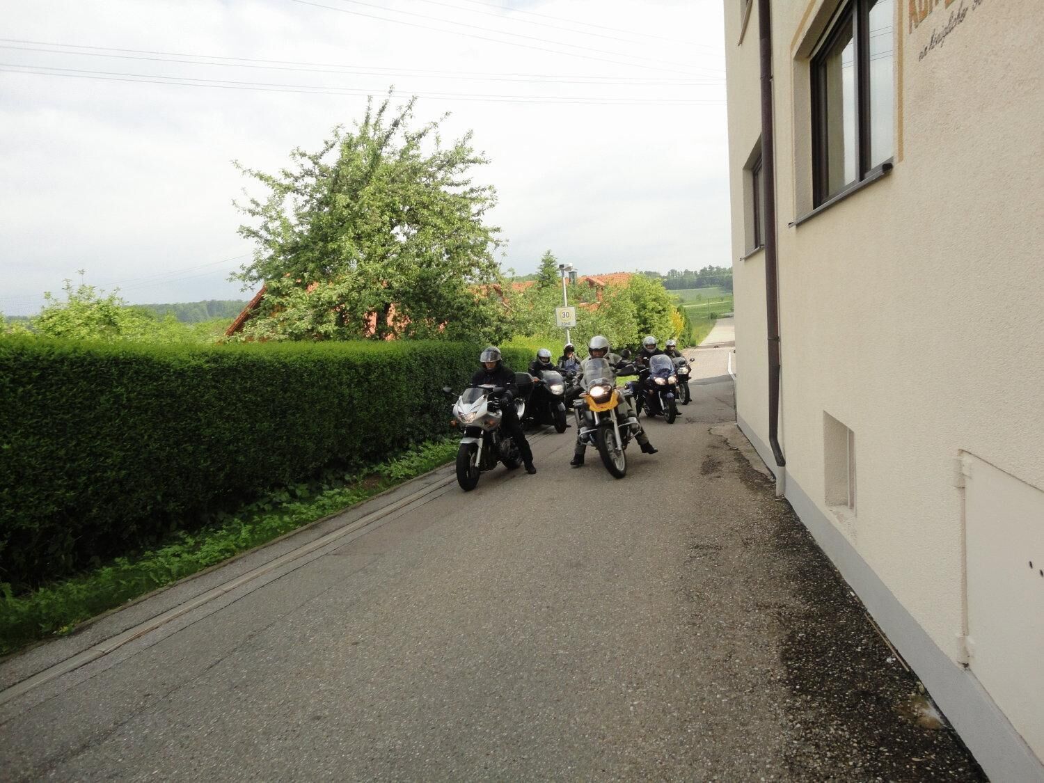 Un groupe de motos était stationné le long d’une route étroite, à côté d’un immeuble.