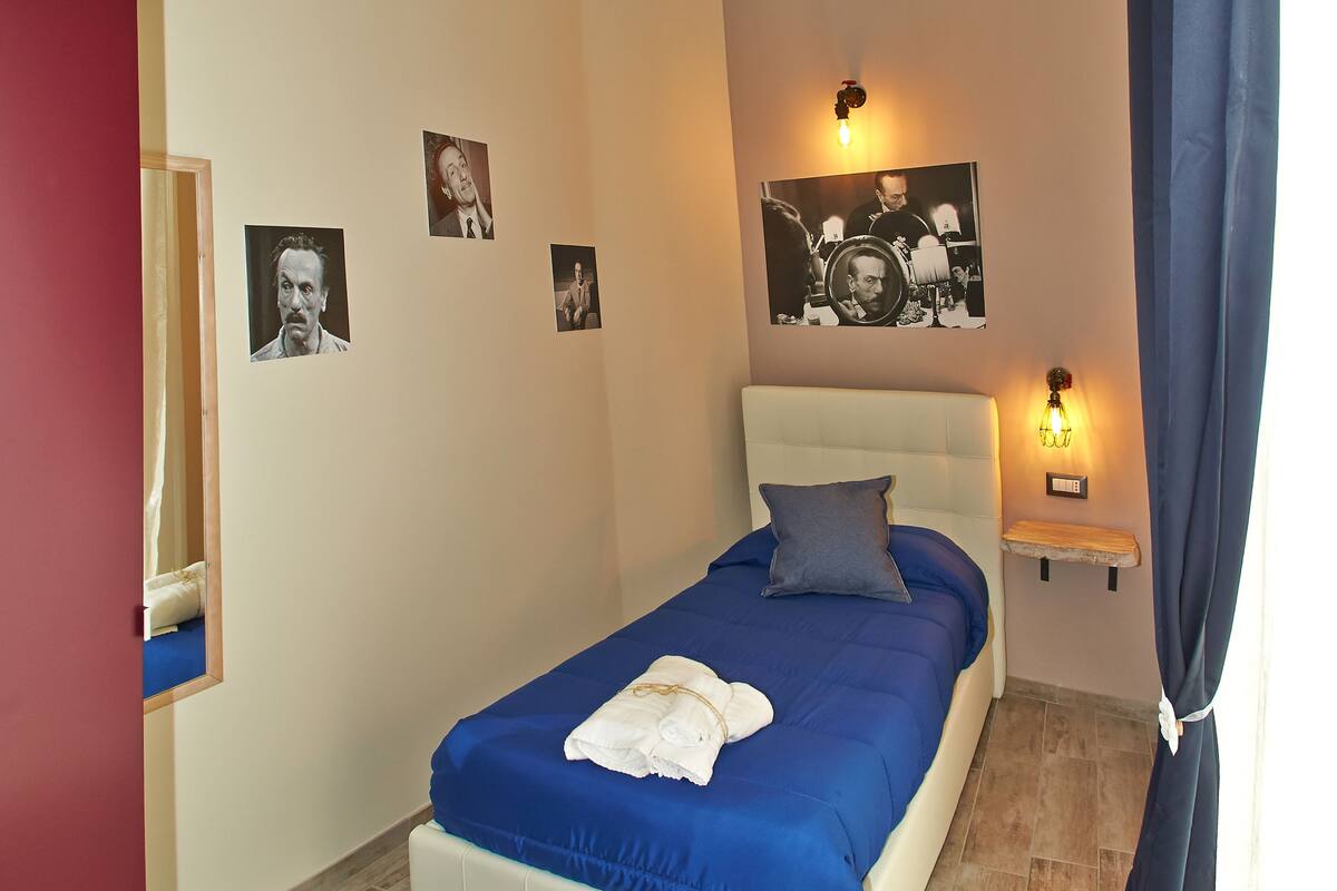 A bedroom with a bed, a nightstand, and wall art.