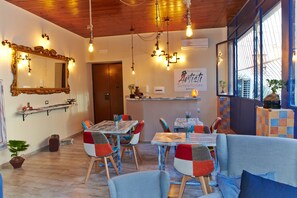 A cozy dining area with wooden tables and colorful chairs, a large mirror, and a sign for 'Artisti Suites & Rooms' in the background. - Artisti Bed&Dreams (Naples)
