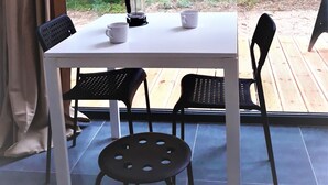A table with four chairs, a coffee maker, and two cups on a balcony with a forest view. - Kaletka (Ilawa)