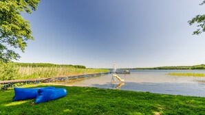 A lakeside view with a dock, inflatable pool, and a water tower in the distance. - Kaletka (Ilawa)