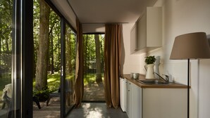 A modern kitchen with a view of a forest through large glass doors, a wooden countertop, and a lamp. - Kaletka (Ilawa)