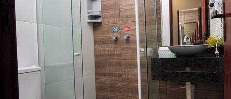 Un baño moderno con ducha envuelta en vidrio, inodoro blanco y tocador con espejo.