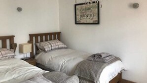 A bedroom with two single beds, a chandelier, and a framed quote on the wall.