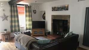 A living room with a sofa, a television, a fireplace, and a star decoration on the wall.