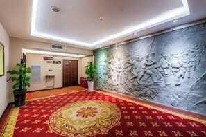 A hotel lobby with a red carpet, a wall mural, and a reception desk. - Jincheng Hotel (Zunyi)