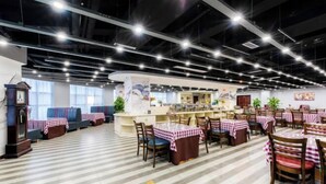 A restaurant with a checkered tablecloth-covered dining area, a central counter, and a clock on the left. - Jincheng Hotel (Zunyi)