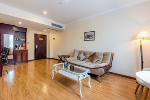A spacious living room with a sofa, a coffee table, and a lamp. - Jincheng Hotel (Zunyi)