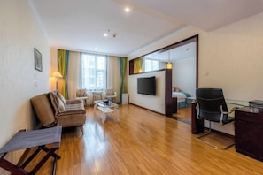 A modern living room with a sofa, coffee table, and a TV mounted on the wall. - Jincheng Hotel (Zunyi)