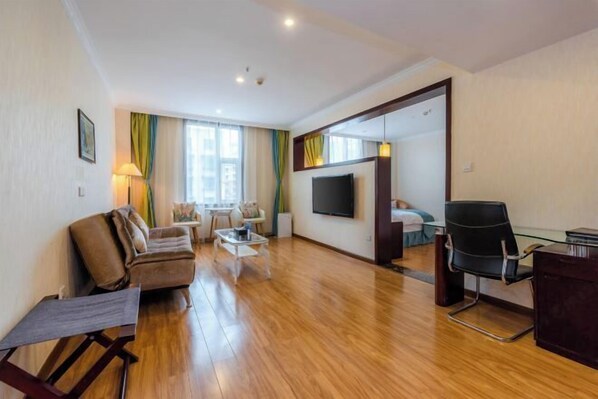 A modern living room with a sofa, coffee table, and a TV mounted on the wall. - Jincheng Hotel (Zunyi)