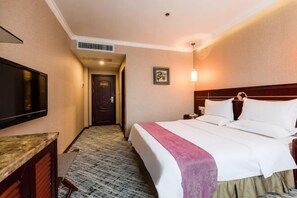 A hotel room with a bed, a desk, a television, and a door leading to another room. - Jincheng Hotel (Zunyi)