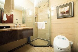 A bathroom with a glass-enclosed shower, a white toilet, a sink with a mirror, and a framed picture on the wall. - Jincheng Hotel (Zunyi)