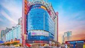 A multi-story hotel with a prominent curved glass facade, signage for a casino, and a visible entrance. - Jincheng Hotel (Zunyi)