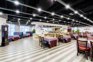 Un restaurante con barra central, varias mesas con manteles a cuadros y un suelo a rayas.