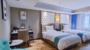 A hotel room with two beds, a desk with a chair, a small table, and a sofa. - Jincheng Hotel (Zunyi)