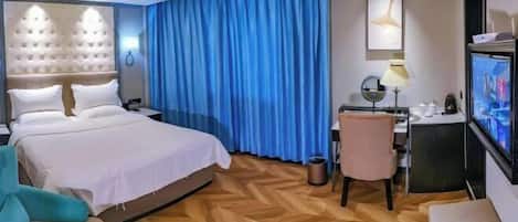 Una habitación de hotel con una cama grande, un escritorio con una computadora, un televisor y una silla.
