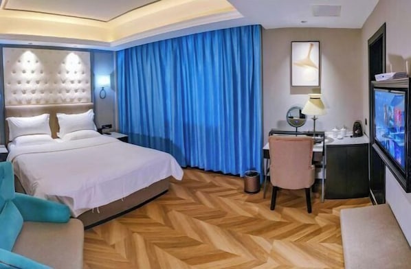 A hotel room with a large bed, a desk with a computer, a TV, and a chair. - Jincheng Hotel (Zunyi)