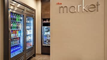 Zona de venta con dispensadores de bebidas refrigeradas y una pared con el texto "the market".