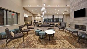 A spacious lobby with a modern design, featuring a large seating area with sofas and chairs, a patterned rug, and a flat-screen TV mounted on the wall. - Residence Inn by Marriott Cincinnati Northeast/Mason (Mason)