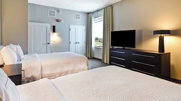Une chambre d’hôtel avec deux lits, une télévision, une commode et une fenêtre avec des rideaux.
