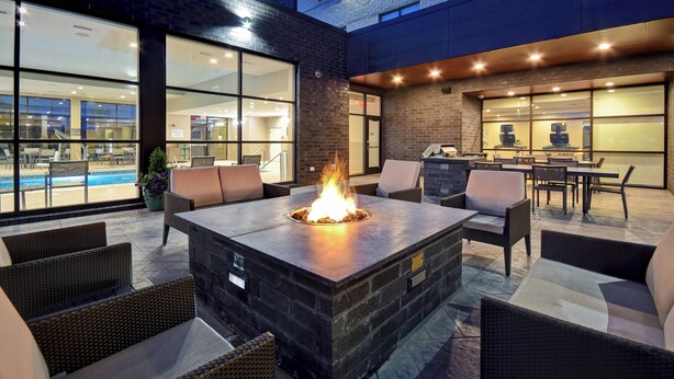 An outdoor patio with a stone fire table, wicker furniture, and a pool view. - Residence Inn by Marriott Cincinnati Northeast/Mason (Mason)