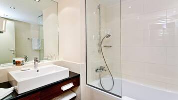 Un baño moderno con un lavabo, tocador y zona de ducha con mampara de vidrio.