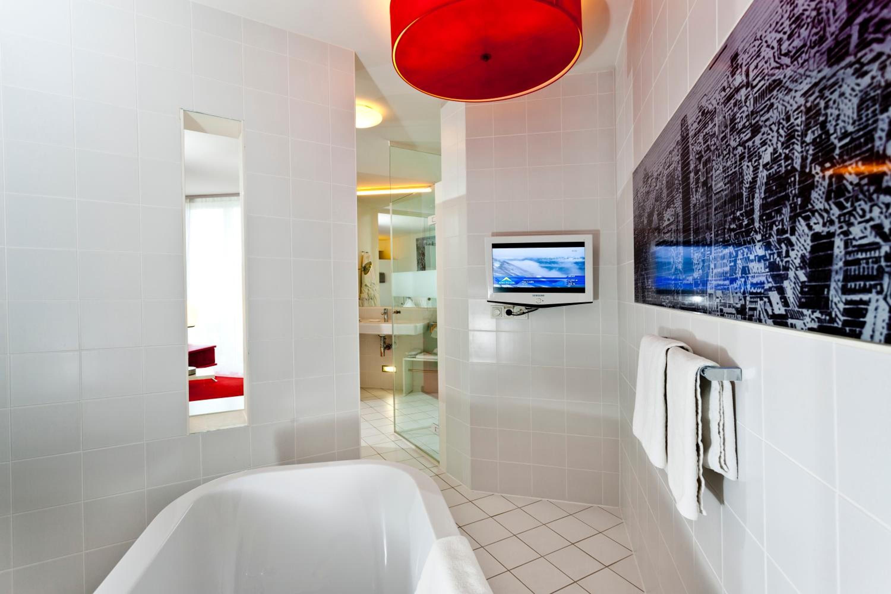 A modern bathroom with a bathtub, a shower, and a large mirror.