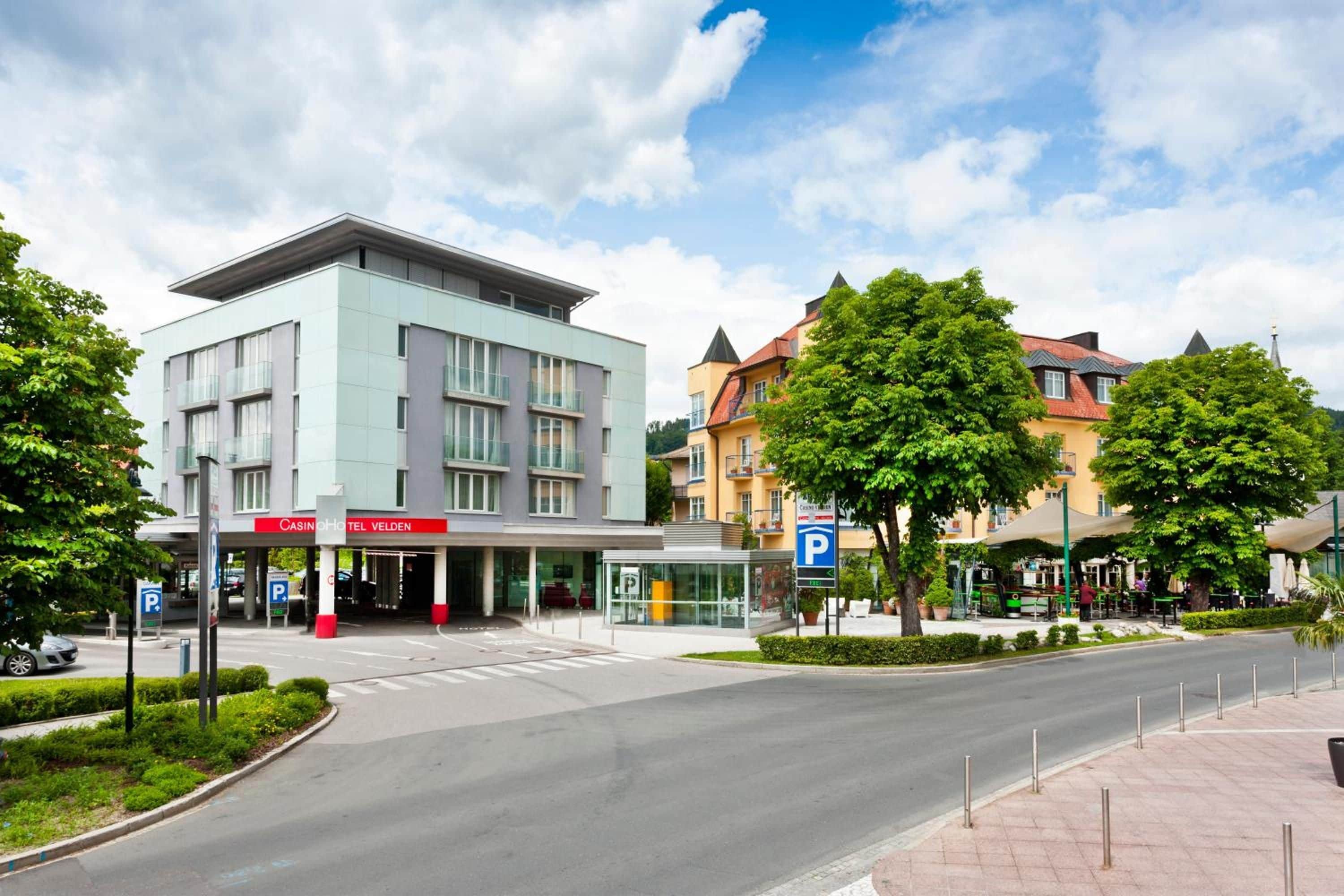 A modern hotel with a prominent entrance, a parking sign, and a clear sky.