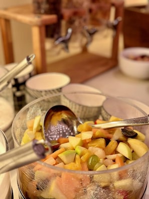 Un tazón de ensalada de frutas con una cuchara.
