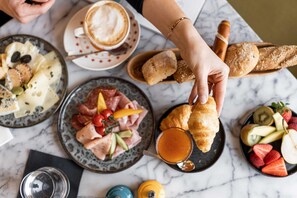 Une table où sont disposés divers aliments, notamment des pâtisseries, des fruits et une tasse de café.