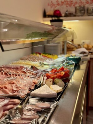 Un bufé con diversos alimentos, incluyendo carnes, quesos y verduras.