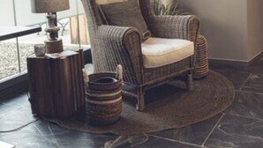 A cozy room with a large window, a wicker chair, a small side table with a lamp, and a rug on the floor. - Hotel Freihof (Prichsenstadt)