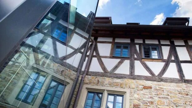 A traditional half-timbered building with a stone facade and a modern glass extension. - Hotel Freihof (Prichsenstadt)