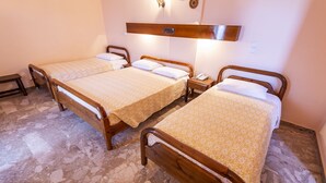 A room with three wooden beds, each with a patterned bedspread and white pillows.