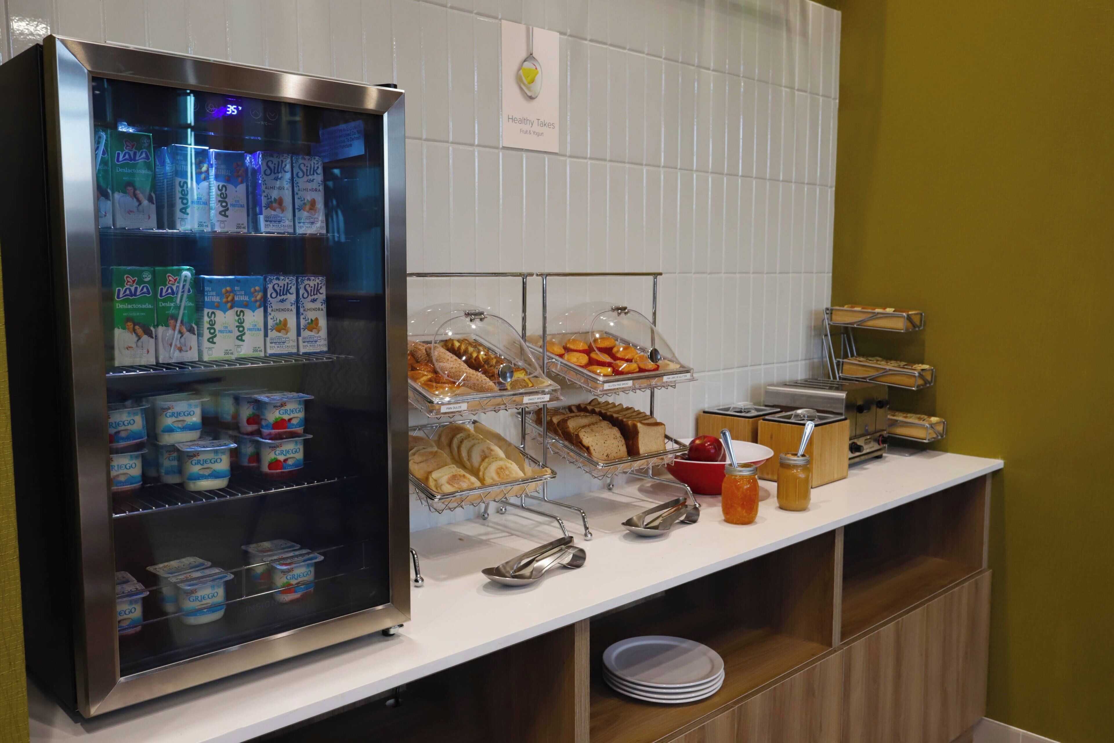 A breakfast buffet with yogurt, bread, and fruit.