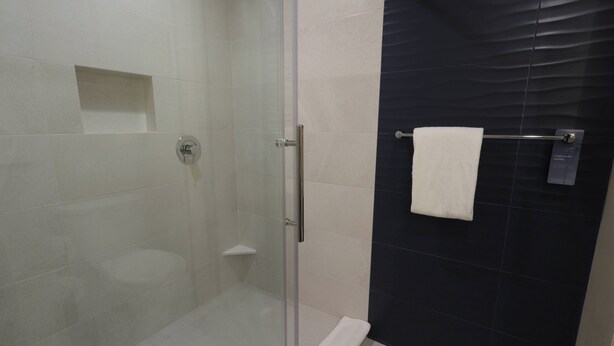 A modern bathroom with a glass-enclosed shower, a white toilet, and a towel rack with a white towel. - Fairfield Inn & Suites by Marriott Mexicali (Mexicali)