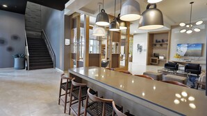 A modern kitchen with a large island, bar stools, pendant lighting, and a staircase leading to an upper level. - Fairfield Inn & Suites by Marriott Mexicali (Mexicali)