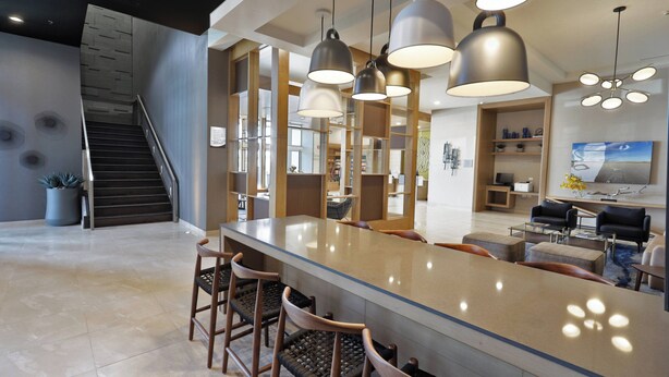 A modern kitchen with a large island, bar stools, pendant lighting, and a staircase leading to an upper level. - Fairfield Inn & Suites by Marriott Mexicali (Mexicali)