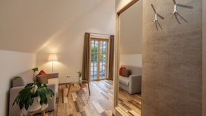 A modern living room with a glass coffee table, two sofas, a floor lamp, and a large sliding door leading to a balcony. - Hotelmyhome (Hornberg)