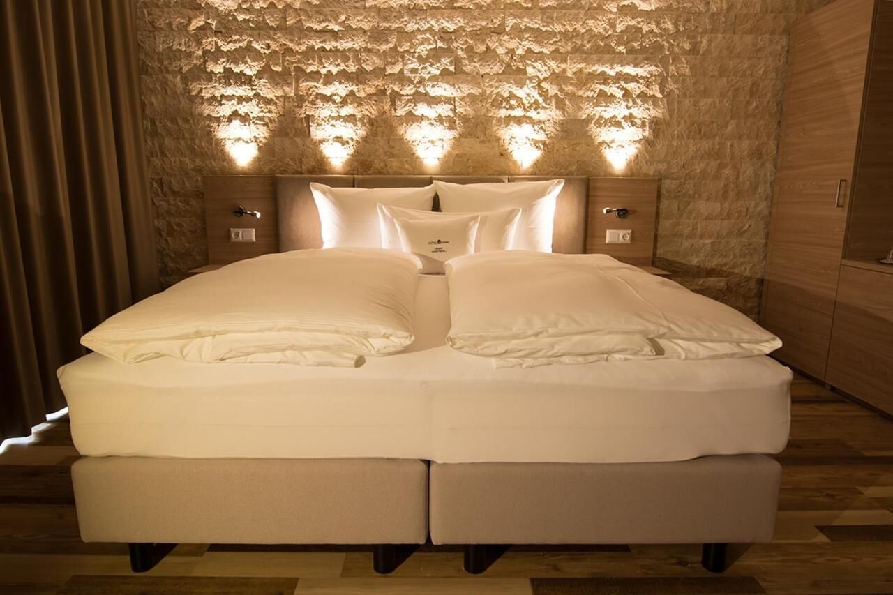 Una cama doble con cabecera de diseño que imita piedra y luces integradas.