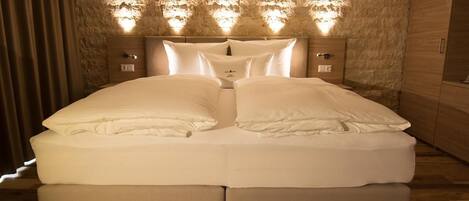 Una cama doble con cabecera de diseño que imita piedra y luces integradas.