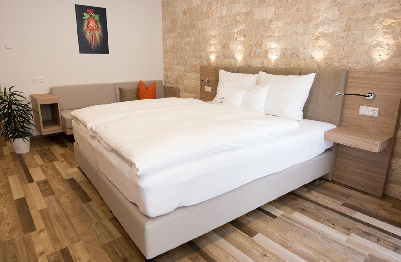Une chambre moderne avec un grand lit, une tête de lit en bois, des tables de chevet et une plante en pot.