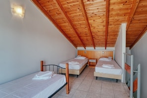 A small, single-room accommodation with two beds, wooden ceiling beams, and a tiled floor.
