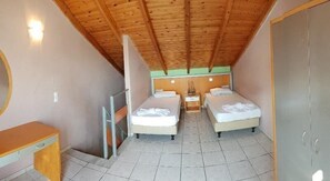 A bedroom with two beds, a wooden ceiling, a bedside table, and a wardrobe.