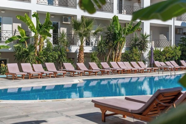 A swimming pool with lounge chairs and palm trees.