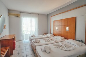 A hotel room with two beds, a wooden headboard, a desk, and a mirror.