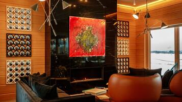 Sala de estar moderna com lareira, uma grande pintura abstrata e vista para uma paisagem nevada através da janela.